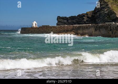 Detaillierte Ansicht der Wellen und der Hafenmauer mit Blick auf Hütte und Küste Detail im Frühsommer. Portreath Beach, Cornwall. Stockfoto