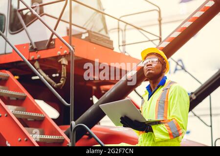 Leiter des Schifffahrtspersonals von Black African Port, der in der Logistik mit einem Laptop arbeitet, um die Verladung von Containern auf dem Schiff für Importexportgüter zu kontrollieren Stockfoto