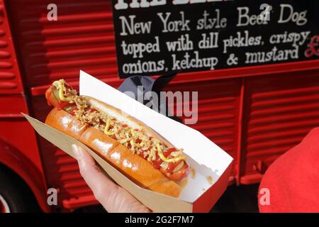 Hand hält einen New Yorker Rindfleisch Hunde er Classic Car Boot Sale am Granary Square in King's Cross London. Stockfoto