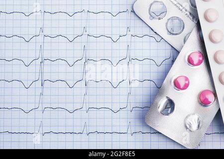 Pillen in Blisterpackungen auf Kardiogramm-Grafik-Papepr-Hintergrund mit Kopieplatz Stockfoto