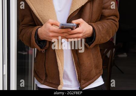 Nahaufnahme der Hände eines jungen Mannes mit Mobiltelefon Stockfoto