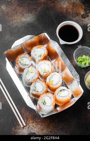 Leckere Sushi-Rollen in Einwegkisten-Set, auf altem dunklen rustikalen Hintergrund Stockfoto