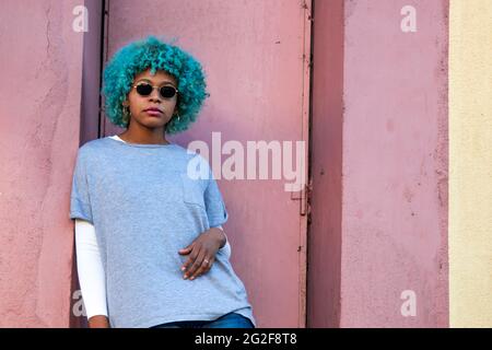 afroamerikanisches Mädchen mit Sonnenbrille und farbigen Haaren auf der Straße Stockfoto