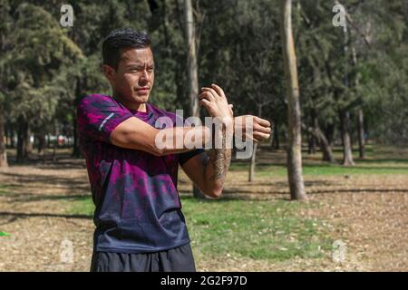 latein fit Mann macht Arm Stretching Übungen. Sich vorbereiten und aufwärmen, bevor man draußen läuft. Stockfoto