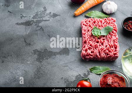 Zutaten für Bolognese-Sauce, Hackfleisch, Tomaten, Kräuter, auf grauem Steingrund, mit Platz für Text Stockfoto