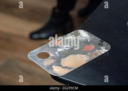 Nahaufnahme von gebrauchten Edelstahl-Make-up-Mischpaletten auf dem Tisch Stockfoto