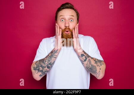 Staunender isolierter Mann mit Bart und weißem T-Shirt Stockfoto