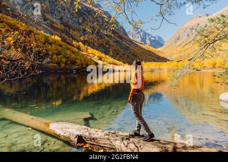 Frau am Kristallsee in den herbstlichen Bergen. Bergsee und Reisende Frau Stockfoto
