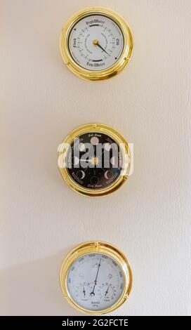 Messinguhr, Mondphasenuhr und Barometer an einer Wand Stockfoto