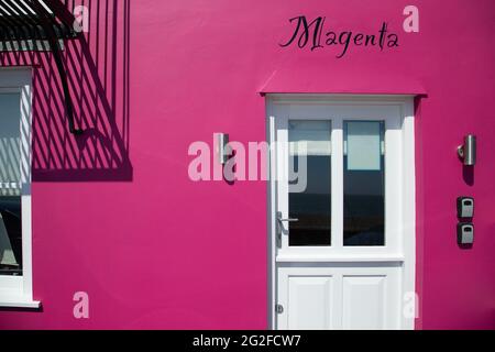 Magentafarbenes altes Haus. Vorderansicht. Bunte alte britische Hausfassade mit Text Magenta darauf. Stockfoto