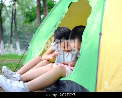 Zwei Kinder spielen mit Tablets im Zelt hochwertige Fotos Stockfoto