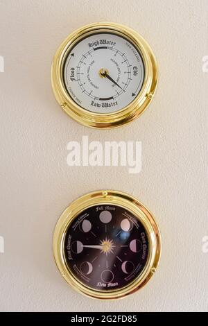 Messinguhr und Mondphasenuhr an einer Wand Stockfoto