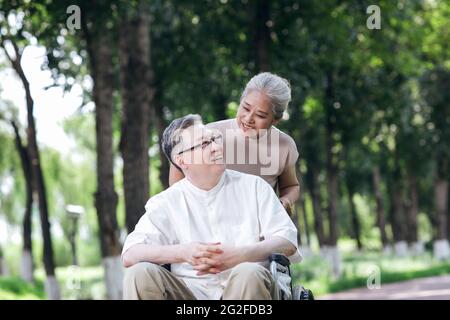 Der alte Mann schiebt seine Frau in einem Rollstuhl hochwertige Foto Stockfoto