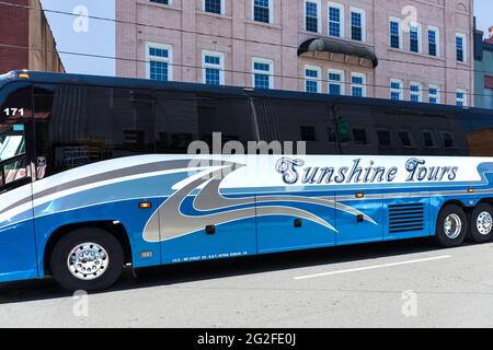 MT. AIRY, NC, USA-5 JUNE 2021: Ein blau glänzender Sunshine Tours Bus fährt die Main Street entlang. Stockfoto