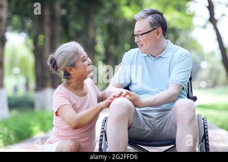 Der alte Mann schiebt seine Frau in einem Rollstuhl hochwertige Foto Stockfoto