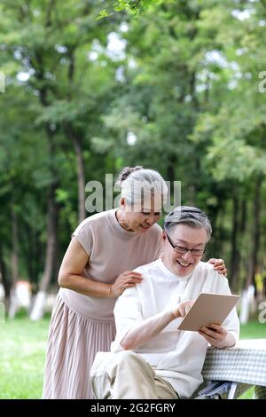Glückliche ältere Paare nutzen Tablet-Computer, um im Freien im Internet zu surfen und Fotos in hoher Qualität zu machen Stockfoto