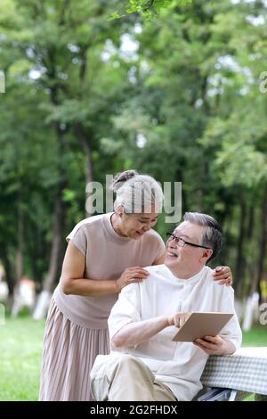 Glückliche ältere Paare nutzen Tablet-Computer, um im Freien im Internet zu surfen und Fotos in hoher Qualität zu machen Stockfoto