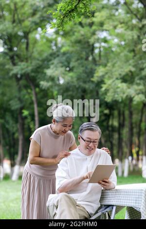 Glückliche ältere Paare nutzen Tablet-Computer, um im Freien im Internet zu surfen und Fotos in hoher Qualität zu machen Stockfoto