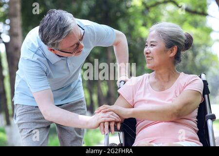 Der alte Mann schiebt seine Frau in einem Rollstuhl hochwertige Foto Stockfoto