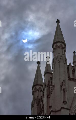 Partielle Sonnenfinsternis wie in Glasgow Scotland am 10/06/2021 Trinity Tower im Vordergrund mit dramatischem Himmel und blauem Fleck durch die Sonne. Stockfoto