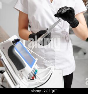 Zahnarzt mit weißen Uniformen und schwarzen Handschuhen, die mit einem All-in-One-Gerätekonzept für die mechanische Wurzelkanalbehandlung arbeiten. Konzept der modernen zahnärztlichen endodontischen Ausrüstung Stockfoto