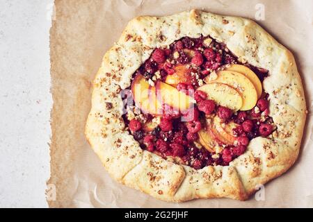 Himbeer- und Pfirsich-Torte, offener Kuchen auf hellem Hintergrund. Stockfoto