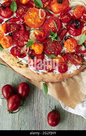 Tomatenpizza mit Käse und Basilikum auf einem Holztisch. Stockfoto