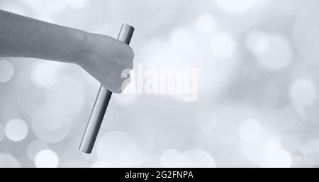Schwarzweiß-Bild der Nahaufnahme der Hand, die einen Schlagstock gegen Bokeh-Lichtflecken im Hintergrund hält Stockfoto