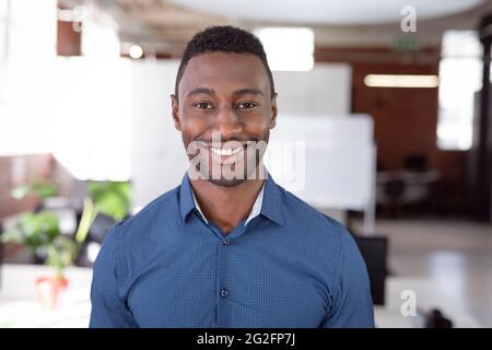 Porträt eines afroamerikanischen Geschäftsmannes, der im Büro steht und lächelt vor der Kamera Stockfoto
