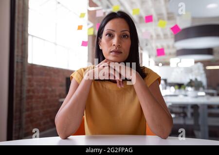 Seriöse kaukasische Geschäftsfrau, die am Schreibtisch sitzt und sich an den Händen lehnt und während eines Videoanrufs zuhört Stockfoto
