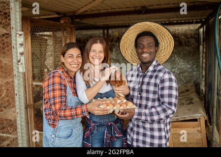 Glückliche, vielfältige Bauern, die in der Nähe des Hühnerstall stehen Stockfoto