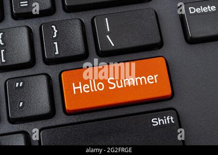 Orangefarbene Taste mit „Hello Summer“-Worten auf einer schwarzen Desktop-Computer-Tastatur. Heiße Sommersaison Reisen, Urlaub, Urlaub Konzepte. Nachricht auf ENTER-Taste Stockfoto