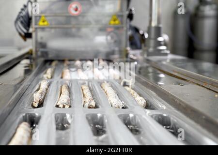 Würstchen. Verpackungslinie von Würsten Fuet ist eine katalanische dünne, gehärtete, trockene Wurst von Schweinefleisch in einem Schweinedarm . Industrielle Herstellung von Wurstwaren. Hochwertige Fotos. Stockfoto