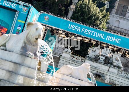 Rom, Italien. Juni 2021. Auf einem Denkmal auf der Piazza del Popolo sind wasserspukende Löwen zu sehen, während im Hintergrund ein Transparent mit der Aufschrift „UEFA Festival Romee“ steht. Das Festival, das Spielübertragungen, spielende Musiker und Unterhaltung bieten wird, beginnt mit dem ersten Spiel der Europameisterschaft am Abend. Die Fußball-Europameisterschaft beginnt am 11. Juni in Romee mit dem Eröffnungsspiel zwischen der Türkei und Italien. Quelle: Matthias Balk/dpa/Alamy Live News Stockfoto