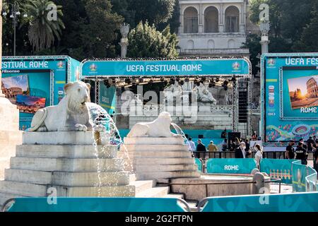 Rom, Italien. Juni 2021. Auf einem Denkmal auf der Piazza del Popolo sind wasserspukende Löwen zu sehen, während im Hintergrund ein Transparent mit der Aufschrift „UEFA Festival Romee“ steht. Das Festival, das Spielübertragungen, spielende Musiker und Unterhaltung bieten wird, beginnt mit dem ersten Spiel der Europameisterschaft am Abend. Die Fußball-Europameisterschaft beginnt am 11. Juni in Romee mit dem Eröffnungsspiel zwischen der Türkei und Italien. Quelle: Matthias Balk/dpa/Alamy Live News Stockfoto