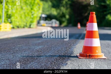 Baukegel markieren einen Teil der Straße mit einer Schicht aus frischem Asphalt. Stockfoto