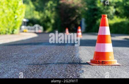 Baukegel markieren einen Teil der Straße mit einer Schicht aus frischem Asphalt. Stockfoto