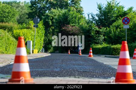 Baukegel markieren einen Teil der Straße mit einer Schicht aus frischem Asphalt. Stockfoto