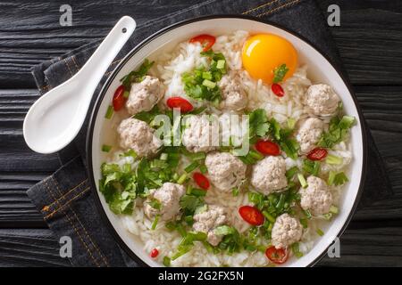 Diätreissuppe mit Fleischbällchen, viel Gemüse und einem Ei aus der Nähe in einer Schüssel auf dem Tisch. Horizontale Draufsicht von oben Stockfoto