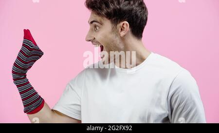 Seitenansicht des aufgeregt Mannes, der die Socke isoliert auf rosa ansieht Stockfoto