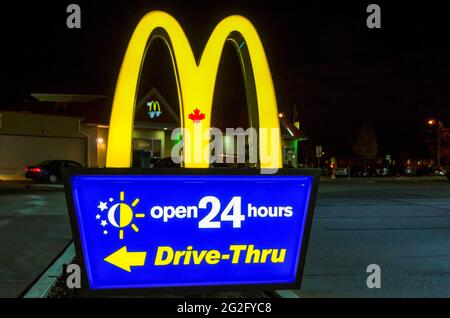 McDonalds Schild mit dem berühmten M Schild auf einer Tafel am Abend. Die McDonald's Corporation ist die weltweit größte Kette von Hamburger Fast Food Stockfoto