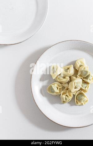 Gekochte Tortellini-Pasta auf einem weißen Teller serviert, bevor die Sauce hinzugegeben wird. Stockfoto