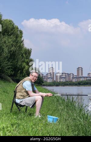 Ein alter Mann fischte am See auf einem qualitativ hochwertigen Foto Stockfoto