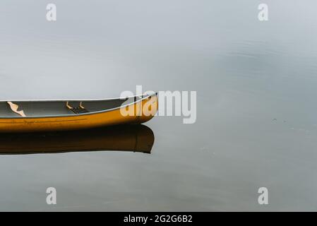 Leeres gelbes Kanu an einem hölzernen Dock an einem ruhigen See in Kanada. Stockfoto