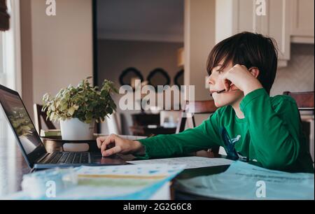 Junge tun auf der Schule Arbeit online am Computer am Küchentisch. Stockfoto