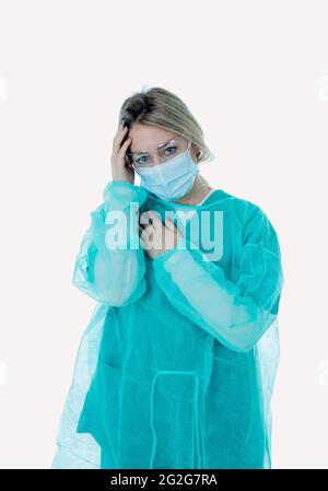 Traurige und überforderte Ärztin oder Krankenschwester, die eine schützende Gesichtsmaske trägt. Depressive und müde Arbeit auf der Intensivstation mit Coronavirus-Patienten. Stockfoto