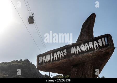 Alanya, Türkei. April 2021. Ein Schild an der Einfahrt nach Damlatas Magarasi mit einer Seilbahn, die im türkischen Badeort Alanya vorbeifährt.der türkische Badeort Alanya, liegt am Fuße des Taurusgebirges an der Mittelmeerküste der Provinz Antalya in der Südtürkei. (Foto von John Wreford/SOPA Images/Sipa USA) Quelle: SIPA USA/Alamy Live News Stockfoto