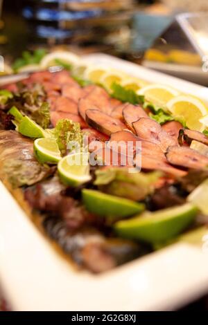 Geräucherter Fisch in Scheiben mit Limette auf einem weißen Teller. Stockfoto