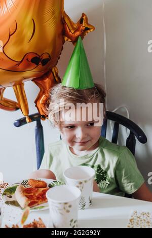 5 Jahre Junge, der in seinem Zimmer spielt, grünes T-Shirt mit Dinosaurier-Print trägt und Geburtstag hat Stockfoto