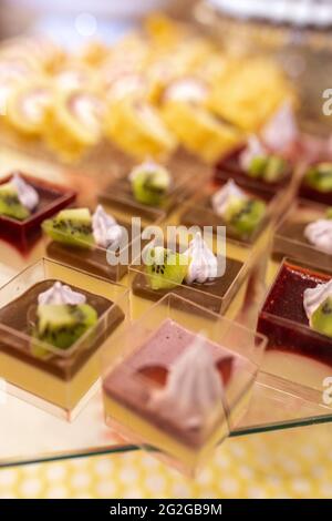 Süße Desserts in Plastikbechern auf einer Kinderparty. Stockfoto
